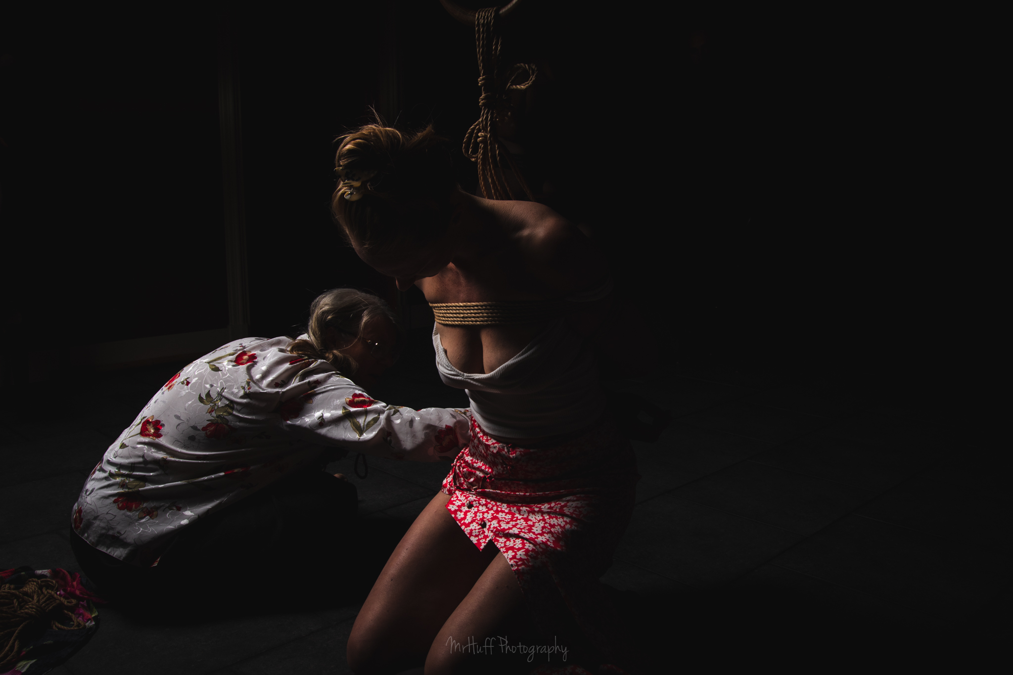 Dramatisch belichte foto van een passievolle shibari show met Jane en Elisabeth
